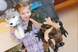 A young girl holding several stuffed animals